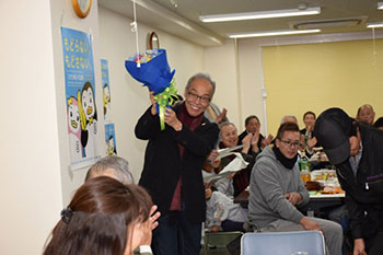 誕生日を祝い，参加者から花束の贈呈の様子