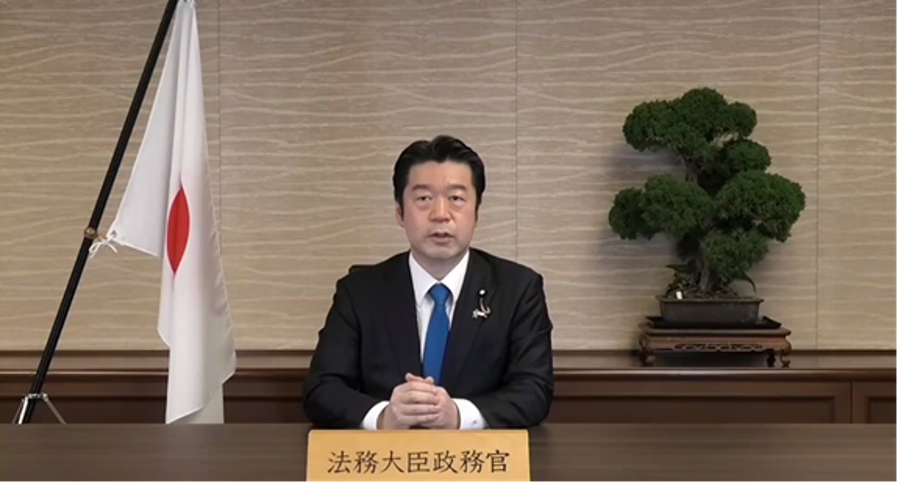 画像:ビデオレターにて開会挨拶を行う加田裕之法務大臣政務官（当時）
