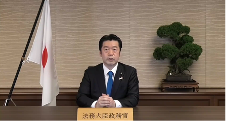 画像:ビデオレターにて開会挨拶を行う加田裕之法務大臣政務官(当時)