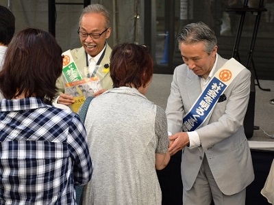来場者に広報資材を配布する谷村新司さん(左)と盛山法務副大臣(右)
