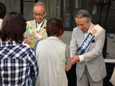 来場者に広報資材を配布する谷村新司さん（左）と盛山法務副大臣（右）