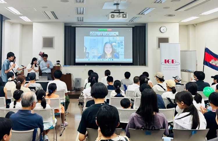 現地からの中継で説明を聞く参加者の様子