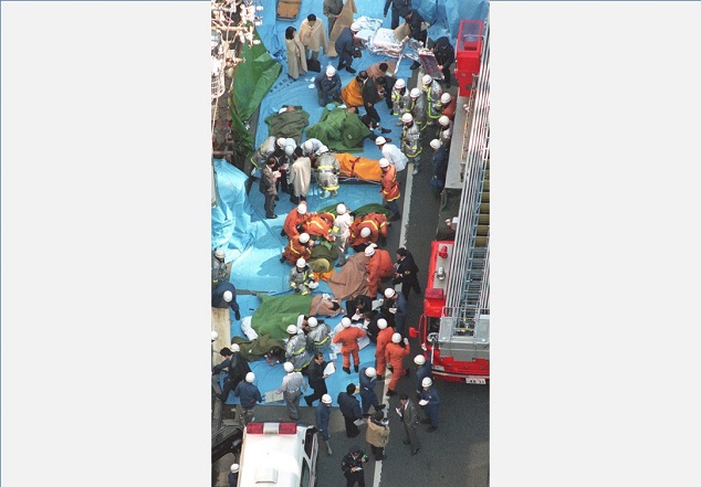路上に横たわる被害者の手当てをする救急隊員（平成7年3月20日、写真：読売新聞/アフロ）